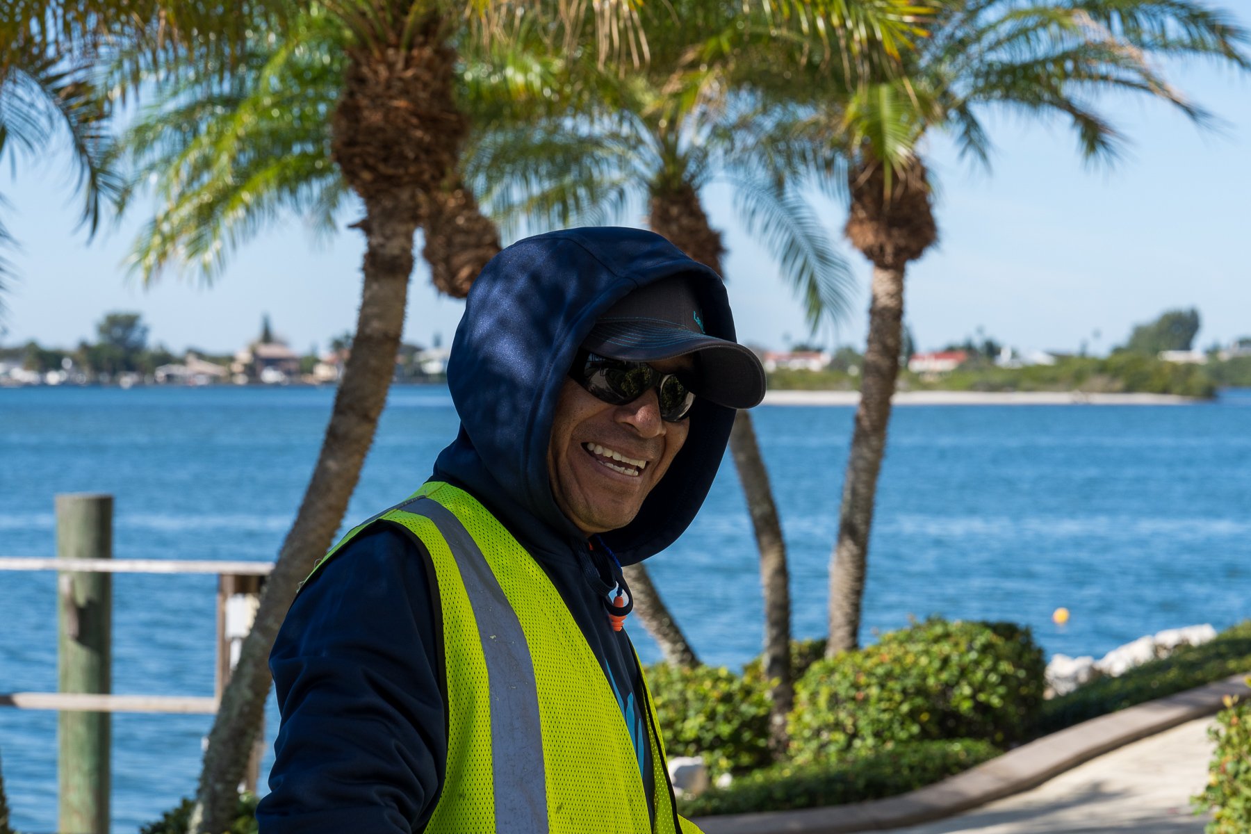 landscape maintenance crew member smiling with palm trees in back